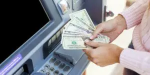 person holding dollar cash in front of an ATM machine